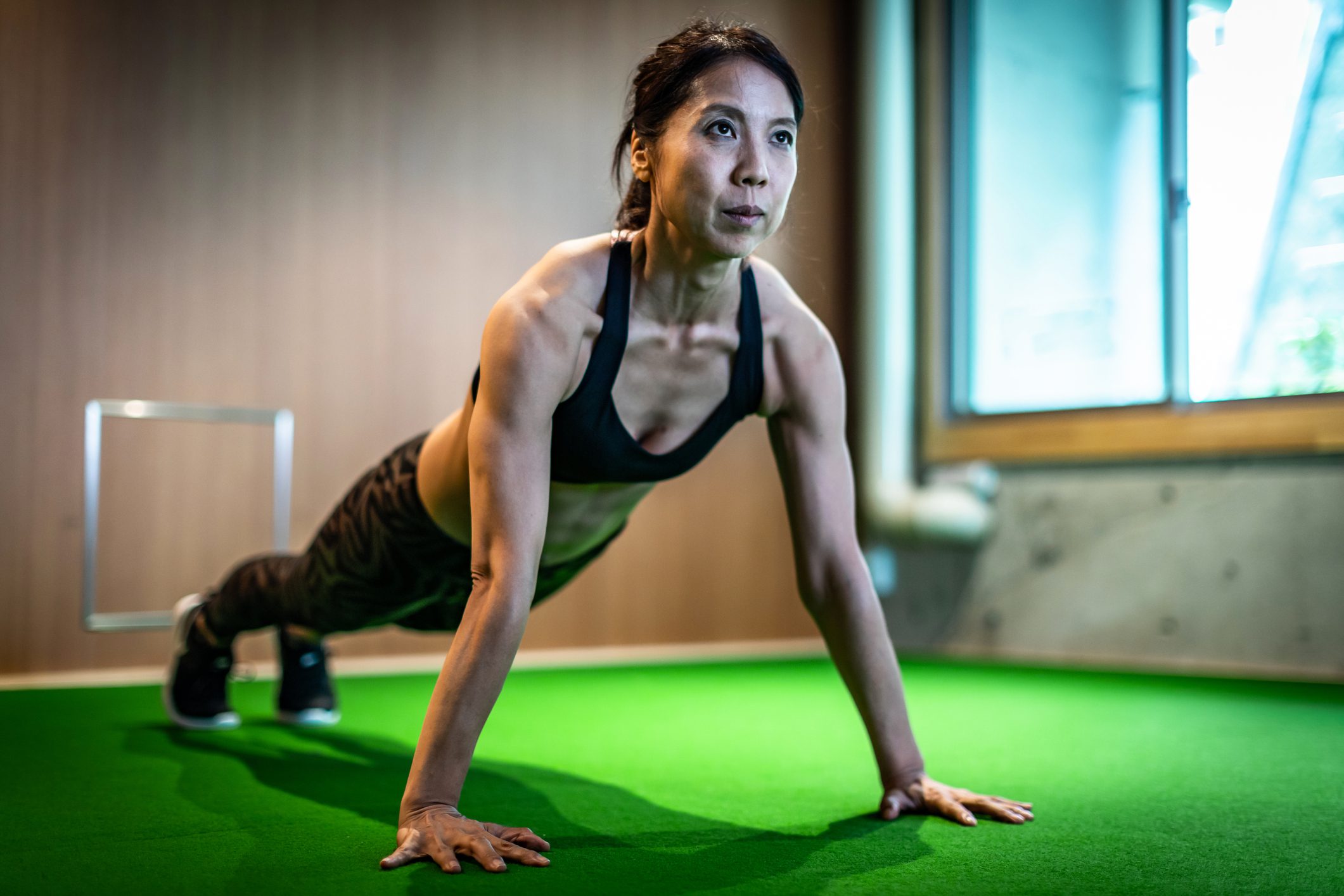 A woman performing push-ups on a green indoor surface, demonstrating strength and fitness.